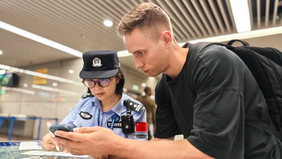 A police officer helps a foreign tourist with entry procedures in Shanghai, east China, July 18, 2025. /Xinhua